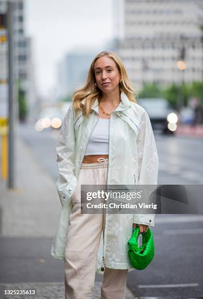 Sonia Lyson is seen wearing sneaker New Balance, Louis Vuitton rain coat, green Bottega Veneta bag, beige jogger pants Pangaia on June 24, 2021 in...