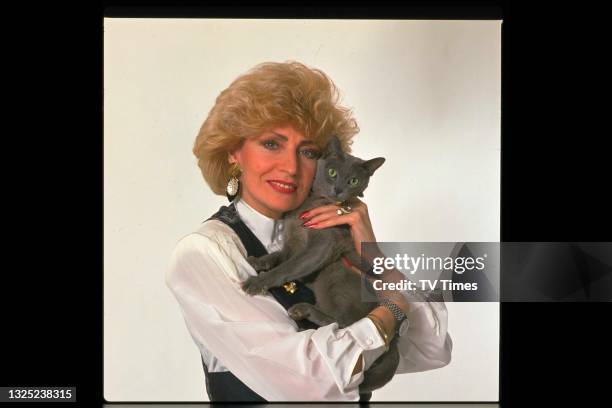 Comic actress and impressionist Faith Brown holding a pet cat, circa 1990.