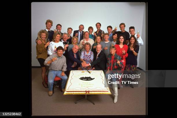 The cast of television soap Emmerdale Farm photographed with a cake for the show's 18th anniversary, circa 1990.