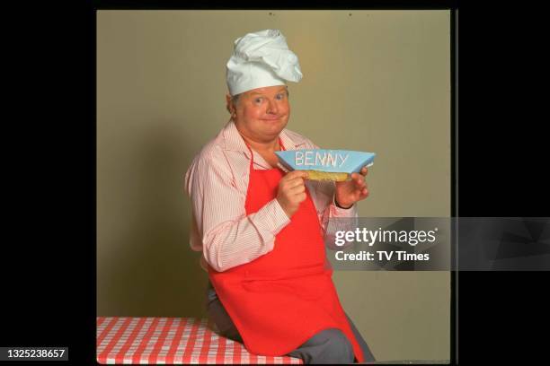 Comedian Benny Hill holding a slice of cake, circa 1988.