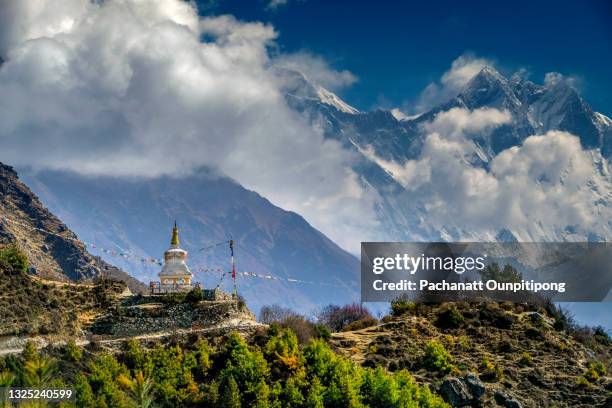 white stupa and prayer flags with himalayan snowcapped mountain at background in sagarmatha national park in nepal - sagarmatha national park stockfoto's en -beelden