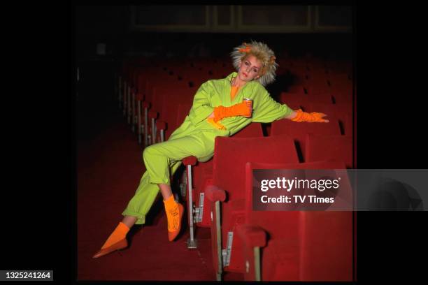 Actress Leslie Ash posed in a cinema wearing a neon green jumpsuit and wrist warmers, circa 1984.