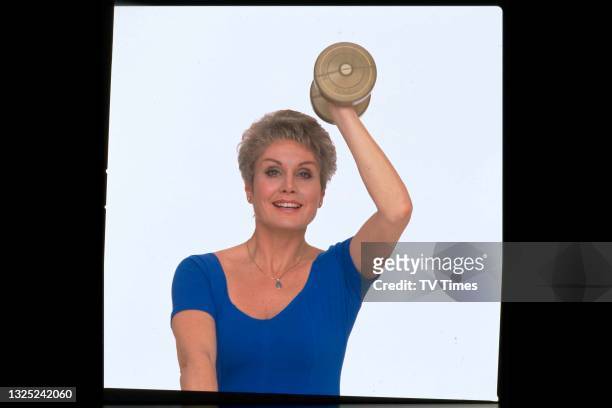 Television presenter and newsreader Angela Rippon exercising with a dumbbell, circa 1991.
