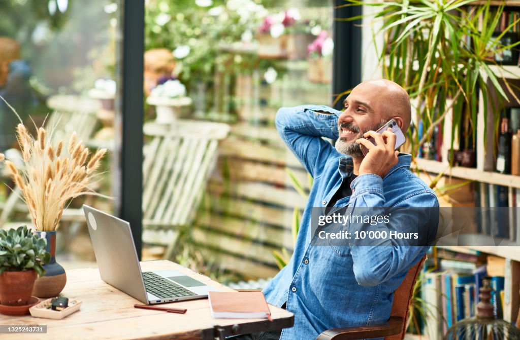 Cheerful businessman talking on mobile phone at home
