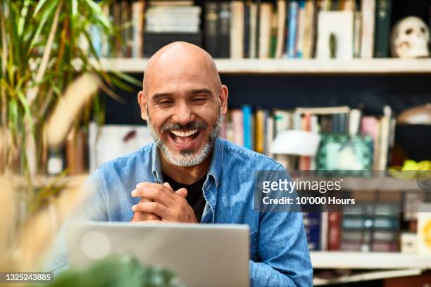 mature man laughing and smiling on video conference - felicidad fotografías e imágenes de stock