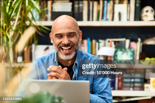 Mature man laughing and smiling on video conference Mature man laughing and smiling on video conference
