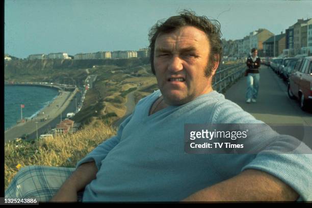 Comedian Les Dawson sitting on bench at Scarborough beach, circa 1976.