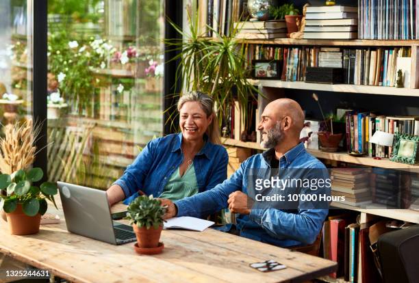 mature couple working from home, talking and laughing - middle age couple fotografías e imágenes de stock