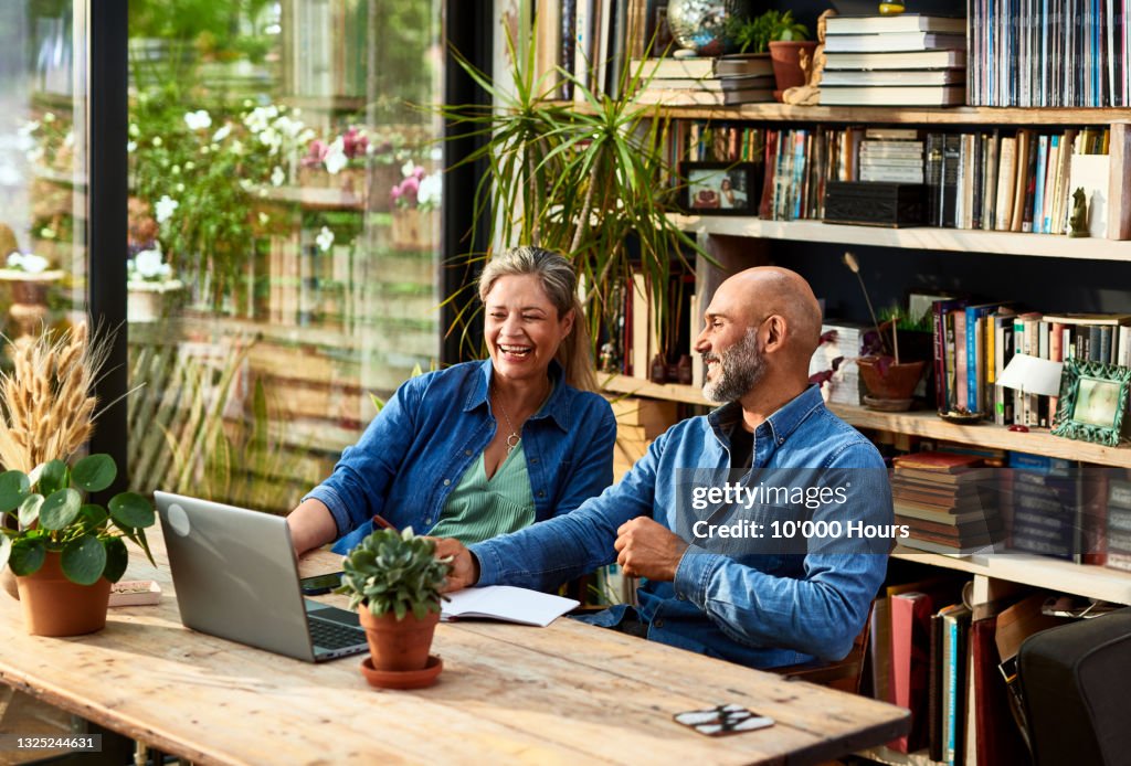 Mature couple working from home, talking and laughing
