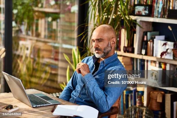 mature businessman sitting at home watching laptop - think ストックフォトと画像