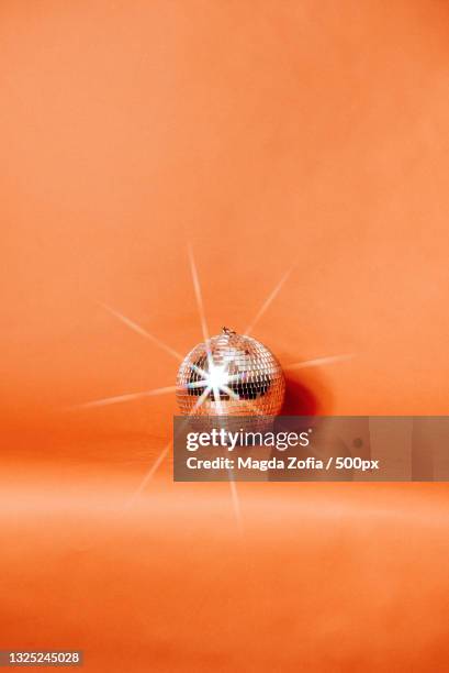 close-up of disco ball on orange background with star reflection - diskokugel stock-fotos und bilder