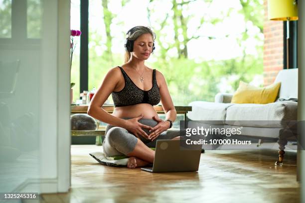 pregnant woman wearing headphones concentrating on breathing exercises - prenatal class stock pictures, royalty-free photos & images