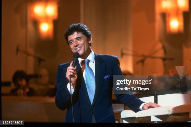 French singer Sacha Distel performing on the set of light entertainment series Des O'Connor Tonight, circa November 1985.