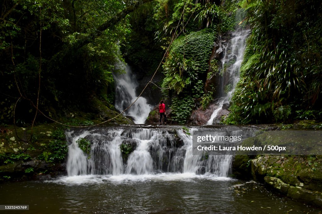 Young woman standing against Elabana Falls in the rain,Lamington National Park,Queensland,Australia