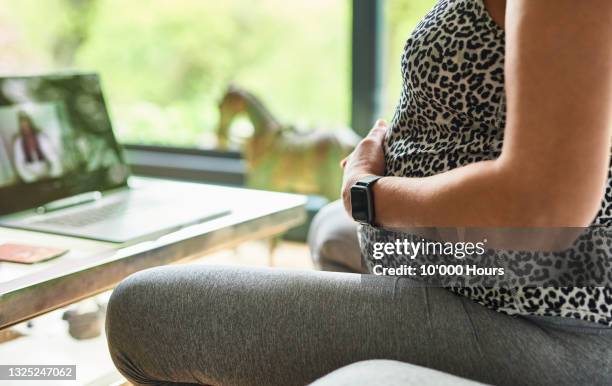 heavily pregnant woman touching baby bump during online doula session - mentoring virtual stock-fotos und bilder