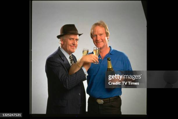 Actors George Cole and Dennis Waterman, co-stars of comedy drama series Minder, drinking champagne circa 1989.