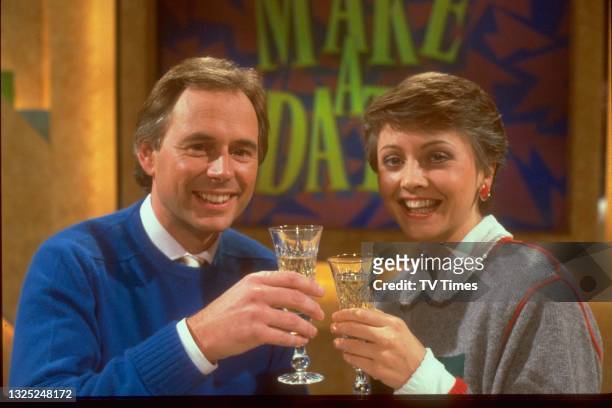 Television presenters Nick Owen and Anne Diamond, co-hosts of Make A Date, celebrating with glasses of champagne, circa 1987.