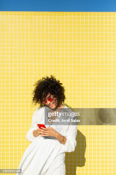 woman taking selfies against a yellow background - summer of love stock-fotos und bilder