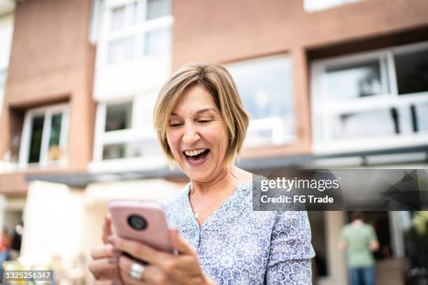 senior woman using smartphone in front of house - be the first stock pictures, royalty-free photos & images