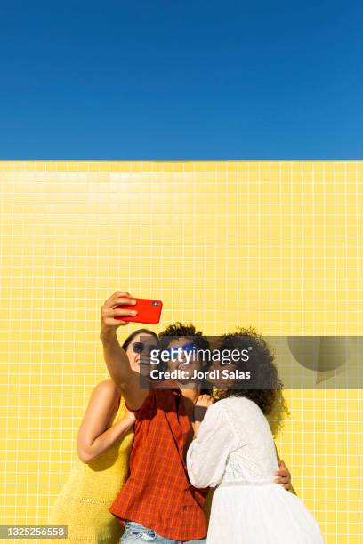 three friends taking a selfie against a yellow background. - friends selfie stock pictures, royalty-free photos & images