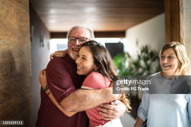 granddaughter embracing grandfather at home - arms around imagens e fotografias de stock