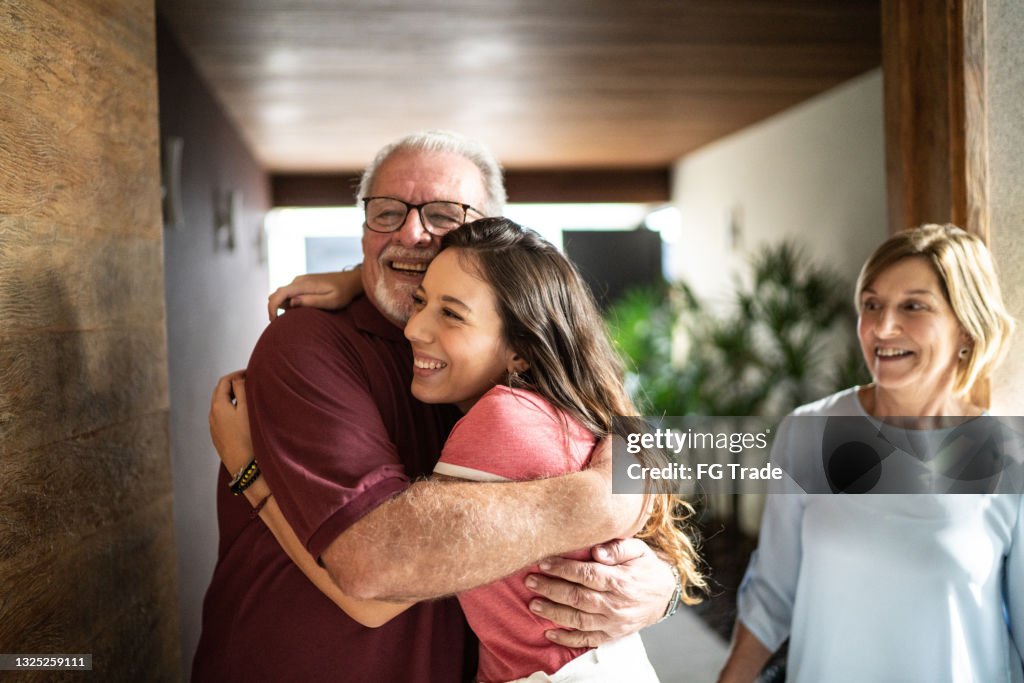 Granddaughter embracing grandfather at home