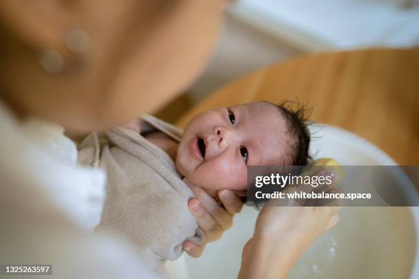 mother washing her little baby girl in a small bathtub. - taking a bath stock pictures, royalty-free photos & images