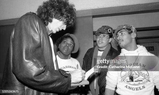 Howard Stern signs an autograph for three unidentified Guardian Angels on November 7, 1987 at an event at which the Guardian Angels present radio...