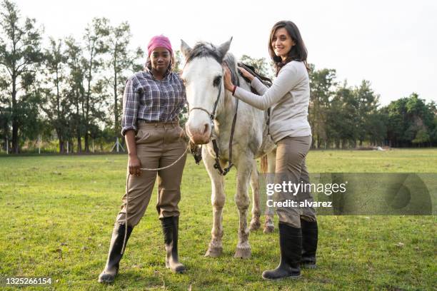 porträt von zwei frauen mit pferd im gestüt - enable horse stock-fotos und bilder