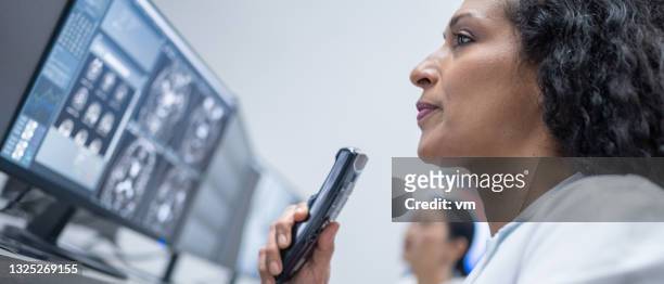 hispanic female medical professional viewing mri scan and recording report on dictaphone. - dictaphone stock pictures, royalty-free photos & images