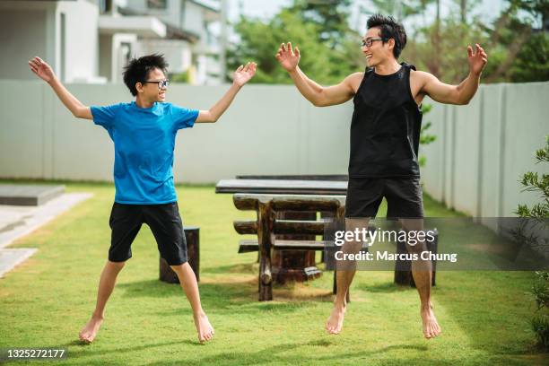 asian chinese father doing jumping jack together with his son in front yard of house - jumping jack stock pictures, royalty-free photos & images