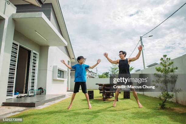 asian chinese father doing jumping jack together with his son in front yard of house - jumping jack stock pictures, royalty-free photos & images