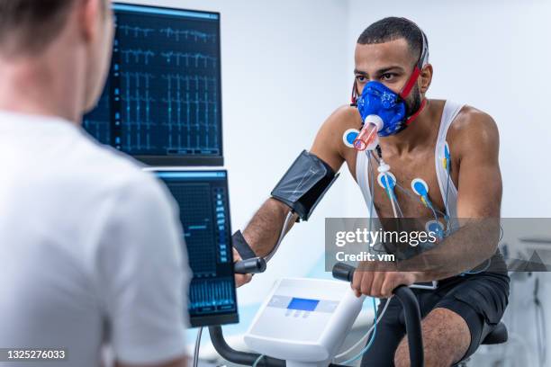 athlete riding an exercise bike in a lab during biometric testing - checking sports stock pictures, royalty-free photos & images