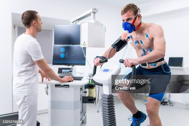 athlete on an exercise bike performing biometric testing - uithoudingsvermogen stockfoto's en -beelden