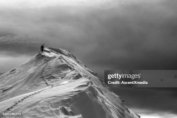 backcountry skier hikes up snowy mountain peak - landscape black and white stock pictures, royalty-free photos & images