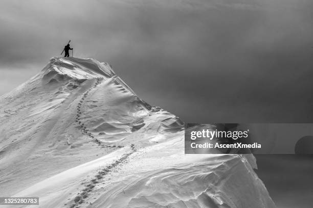 un skieur de l’arrière-pays grimpe sur le sommet enneigé des montagnes - neige épaisse photos et images de collection