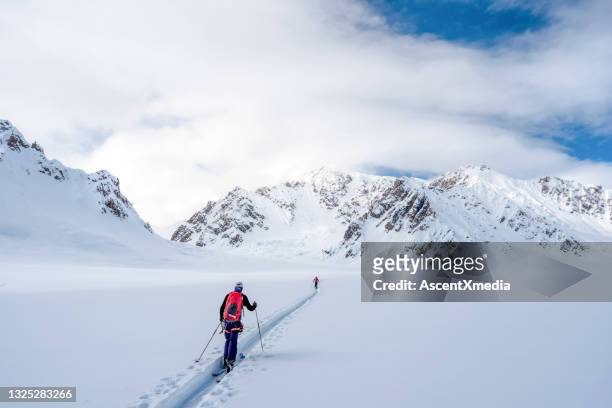 gli sciatori del backcountry scalano le montagne rocciose canadesi innevate - telemark foto e immagini stock