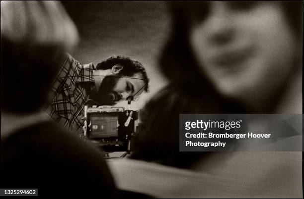 View, between two students, of a teacher looking at a large format camera during a photography class at Moorpark College, Moorpark, California, 1976.