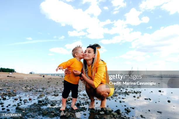 mother with braided hair in yellow outfit with her little son walking in the city park by the sea. - krestovsky stadium view stock pictures, royalty-free photos & images