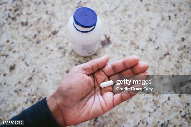 woman holds pill in palm of hand - medicine dose stock pictures, royalty-free photos & images