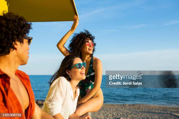 friends hanging out at the lifeguard station on the  beach - retreat women diverse stockfoto's en -beelden