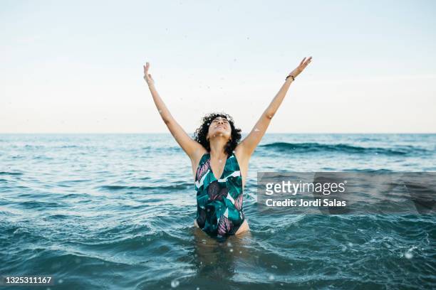woman in the sea splashing water - ocean shore stock-fotos und bilder