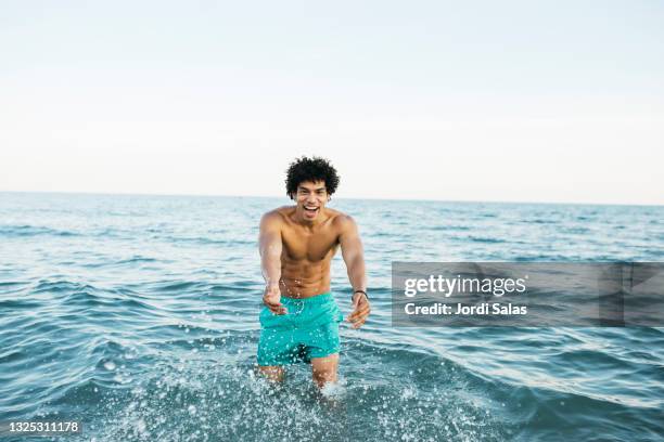 black man  splashing water in the sea - black people in bathing suits stock pictures, royalty-free photos & images