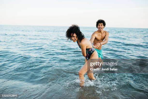 couple playing at the water's edge on the beach - mediterranean stock-fotos und bilder