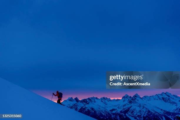 backcountry skier climbs snow slope at sunrise - extreem skiën stockfoto's en -beelden