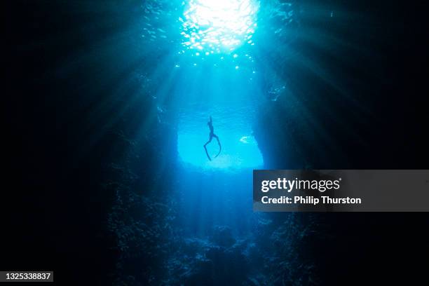 underwater diver swimming through cave towards sunlight - deep dive stock pictures, royalty-free photos & images