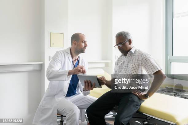 doctor and senior patient discussing medical test results using digital tablet - male patient stock pictures, royalty-free photos & images