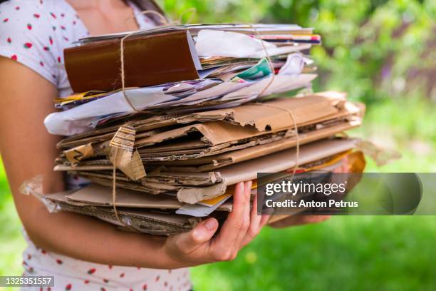 woman holds a stack of paper and cardboard for recycling. - material reciclado imagens e fotografias de stock