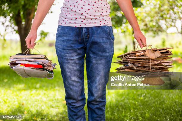 woman holds a stack of paper and cardboard for recycling. - wastepaper basket stock-fotos und bilder