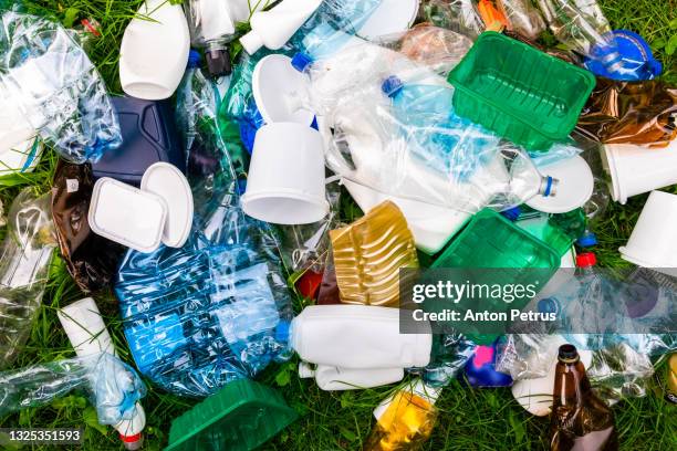 various types of plastic trash on the grass. plastic for recycling. - mixed recycling bin stock pictures, royalty-free photos & images